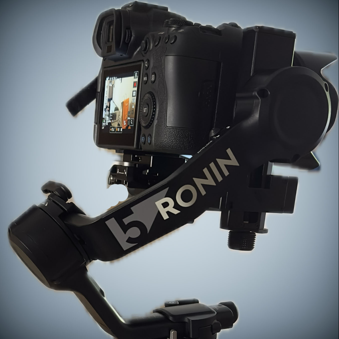 Appareil photo monté sur un stabilisateur Ronin, avec un écran allumé affichant une image.